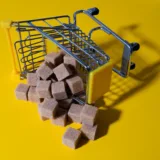 Cuburi de zahăr brun răsturnate dintr-un coș de cumpărături miniatural