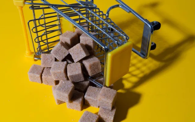 Cuburi de zahăr brun răsturnate dintr-un coș de cumpărături miniatural